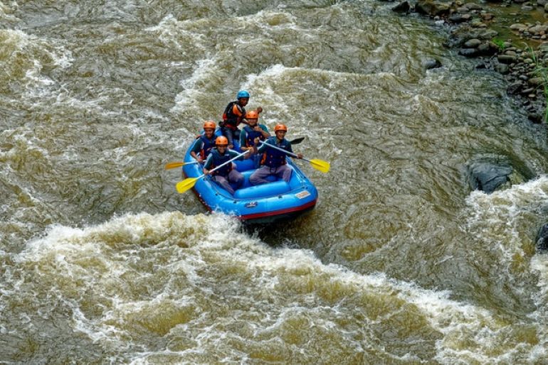 There are several people on an inflatable boat on a river.